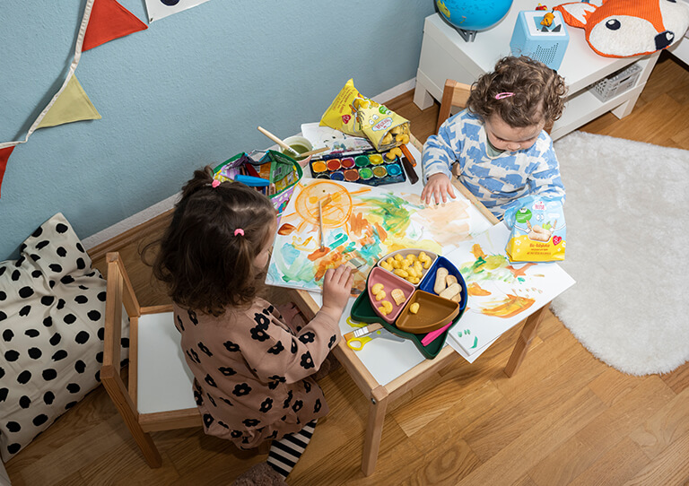 Bio Snacks: Spielspaß und leckere Snacks - Kinder malen gemeinsam und snacken dabei die leckeren Bio Baby Snacks von FruchtBar
